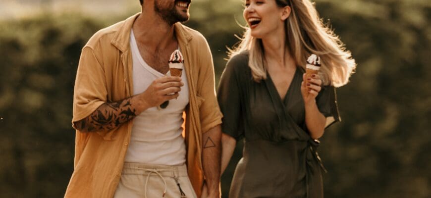 A smiling man and woman walking and holding ice cream cones
